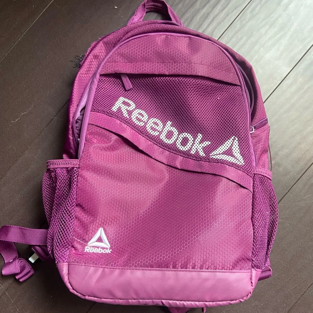 Purple Reebok book bag with tear right near strap